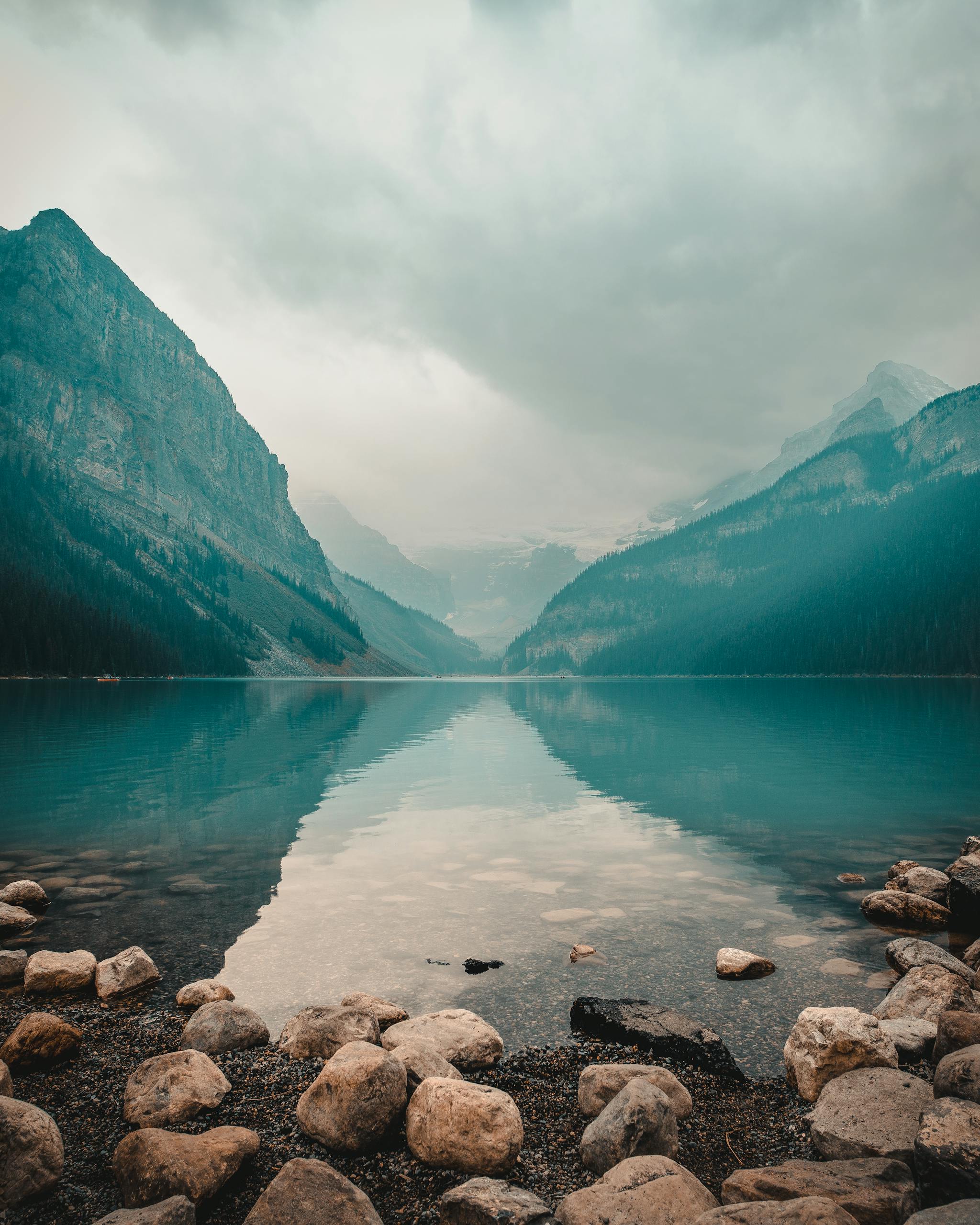 Panoramic view of Lake Louise with mountain reflections and overcast sky.